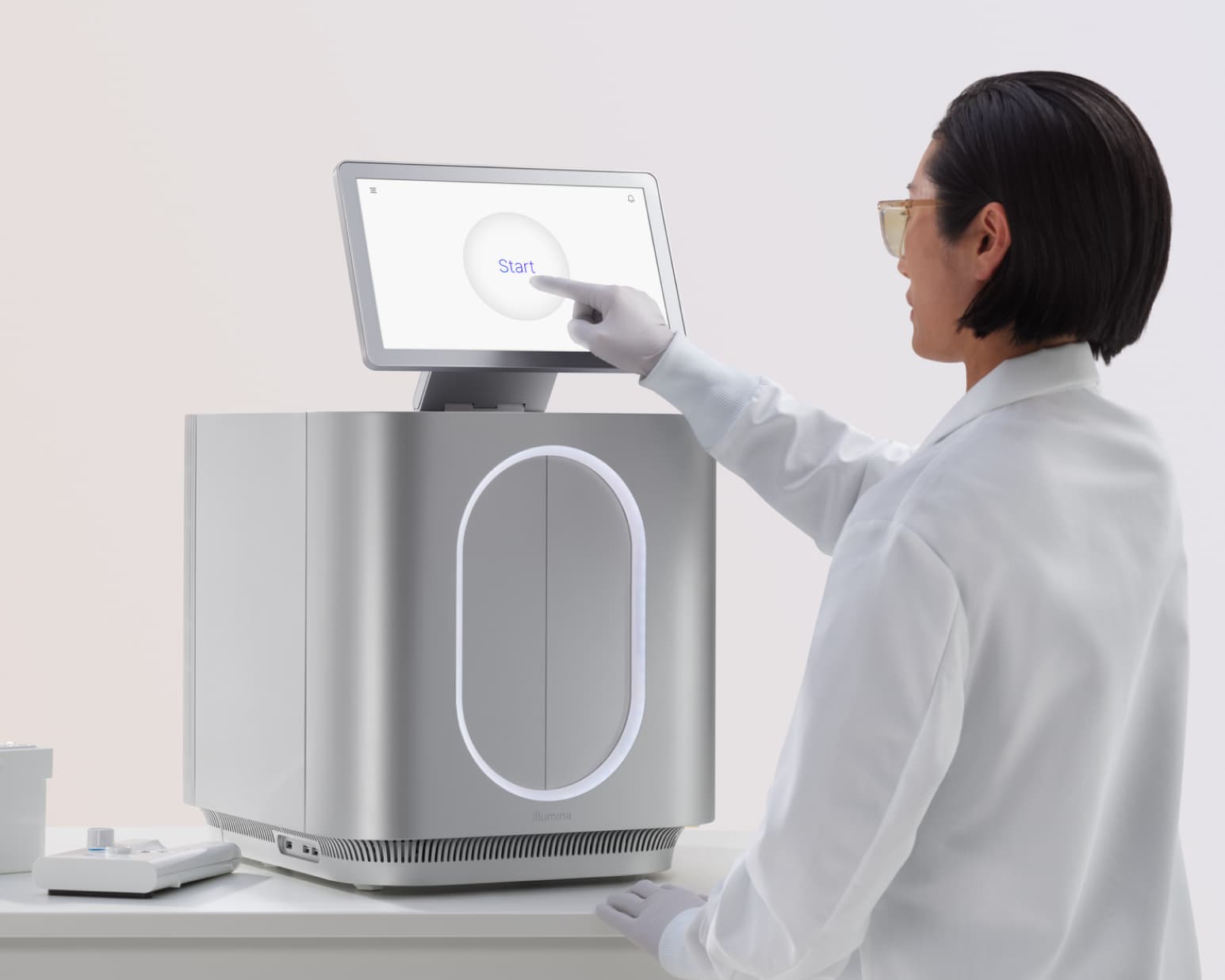 Side view of female scientist touching the start screen, instrument and wet and dry cartridges on lab bench, gradient background.